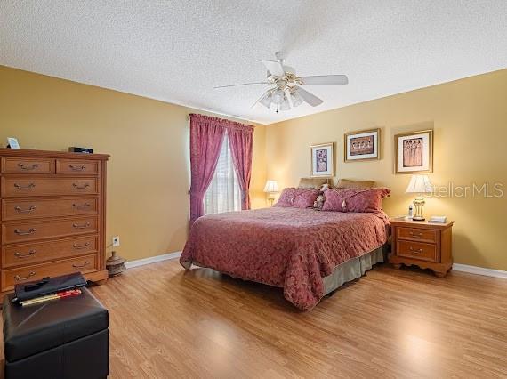 bedroom with ceiling fan, a textured ceiling, and light wood-type flooring