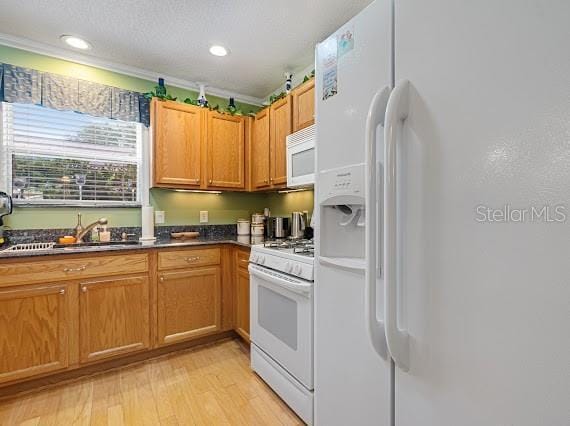 kitchen with crown molding, sink, light wood-type flooring, white appliances, and a textured ceiling