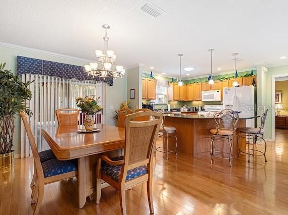 dining space featuring light wood-type flooring and crown molding