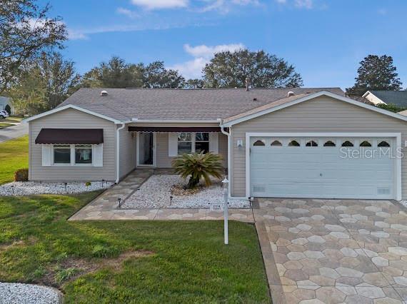 ranch-style house featuring a garage and a front lawn