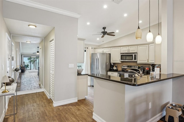 kitchen featuring tasteful backsplash, lofted ceiling, kitchen peninsula, hanging light fixtures, and appliances with stainless steel finishes