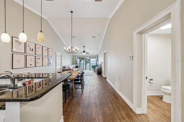 kitchen with hardwood / wood-style flooring, ceiling fan, decorative light fixtures, vaulted ceiling, and ornamental molding