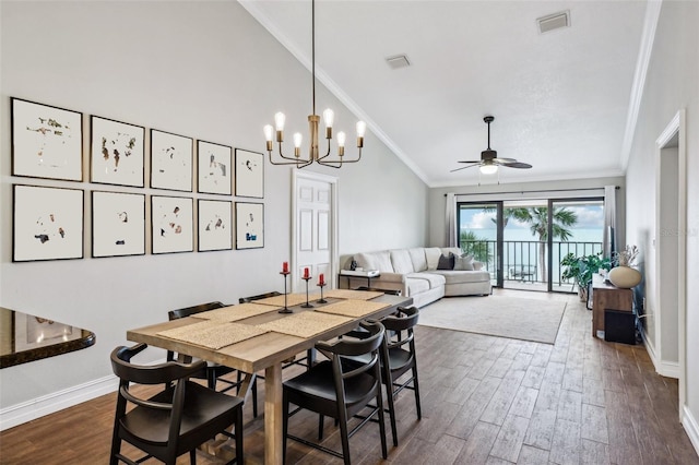 dining room featuring vaulted ceiling, dark wood-type flooring, ornamental molding, and ceiling fan with notable chandelier