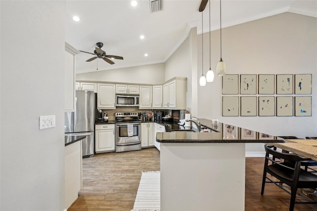 kitchen with white cabinets, decorative light fixtures, stainless steel appliances, sink, and kitchen peninsula