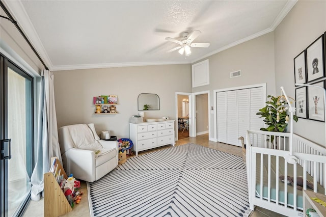 bedroom with a crib, a closet, ornamental molding, and ceiling fan