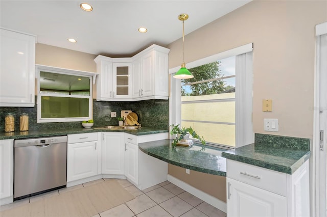 kitchen with decorative backsplash, white cabinets, stainless steel dishwasher, and light tile patterned flooring