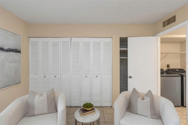 tiled living room featuring a textured ceiling and washer and clothes dryer