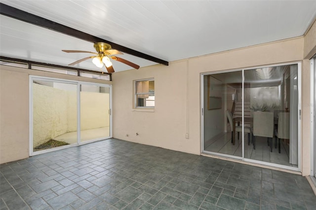 unfurnished sunroom featuring ceiling fan and beamed ceiling