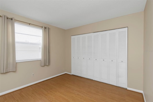 unfurnished bedroom featuring a textured ceiling, a closet, and hardwood / wood-style floors