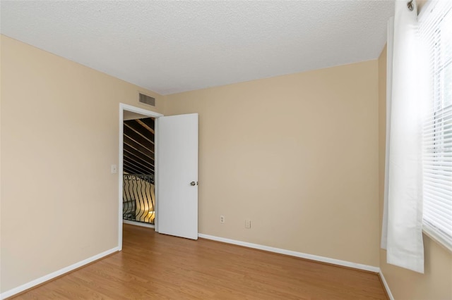 spare room featuring a textured ceiling and light hardwood / wood-style flooring