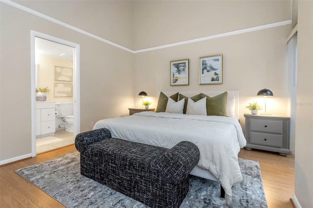 bedroom featuring light wood-type flooring, ensuite bathroom, and ornamental molding