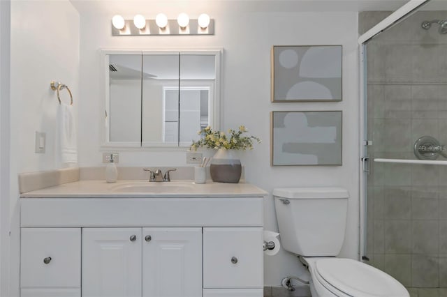 bathroom with toilet, vanity, and an enclosed shower