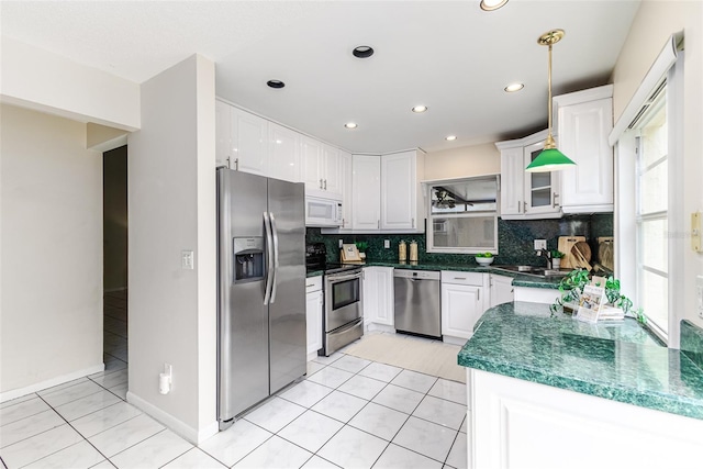 kitchen with hanging light fixtures, white cabinets, appliances with stainless steel finishes, and light tile patterned floors