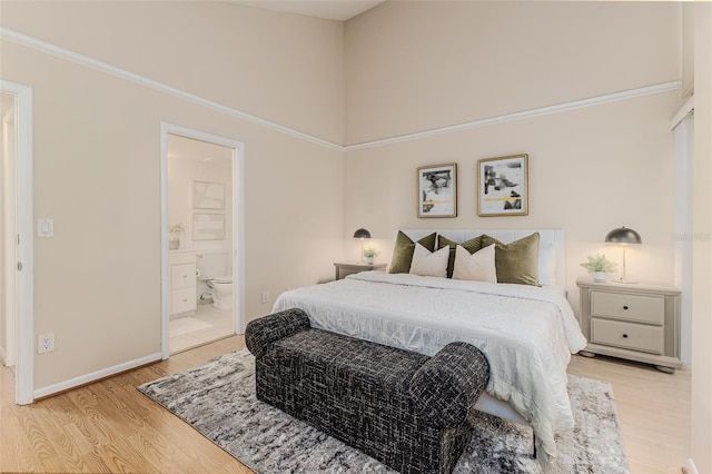 bedroom featuring connected bathroom and light hardwood / wood-style flooring