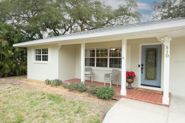 view of exterior entry featuring covered porch and a yard