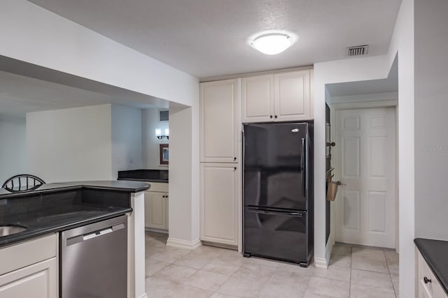 kitchen with white cabinets, light tile patterned floors, black fridge, a textured ceiling, and stainless steel dishwasher