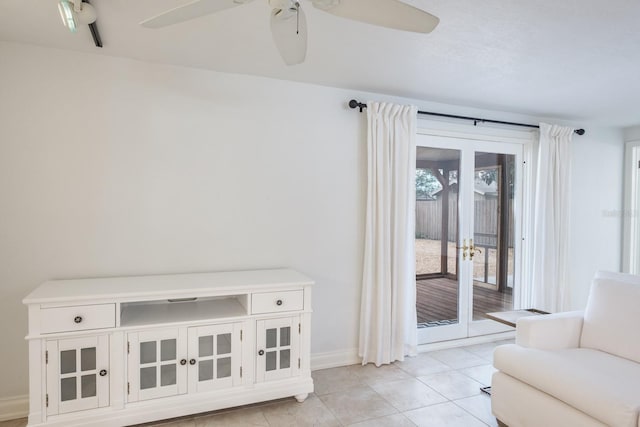 tiled living room featuring ceiling fan and french doors