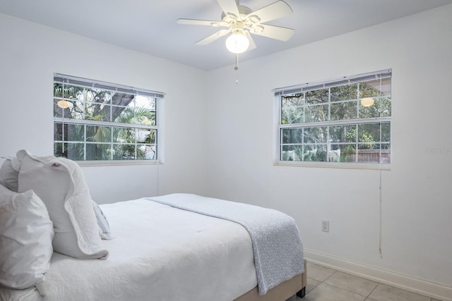 tiled bedroom with ceiling fan and multiple windows