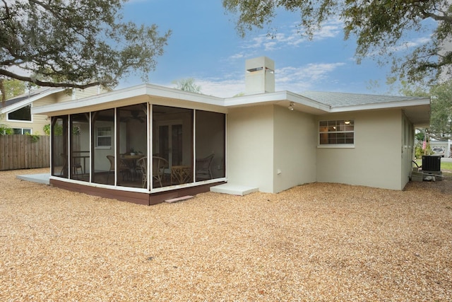 rear view of house with central air condition unit and a sunroom