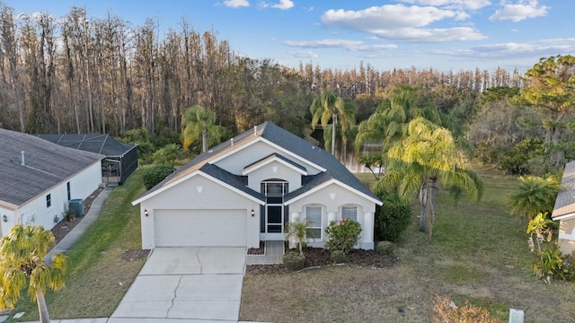 view of front of property featuring central AC unit, glass enclosure, a front lawn, and a garage