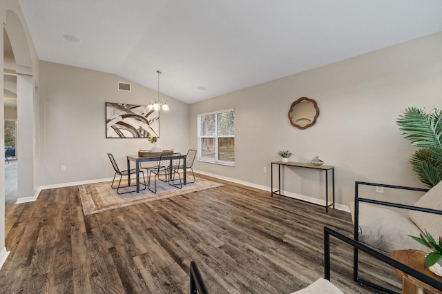 dining area with dark wood-type flooring, lofted ceiling, and a chandelier