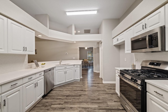 kitchen featuring kitchen peninsula, dark wood-type flooring, a high ceiling, white cabinets, and appliances with stainless steel finishes