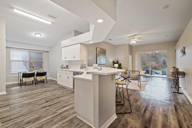 kitchen featuring a breakfast bar area, white cabinets, dark hardwood / wood-style floors, and kitchen peninsula