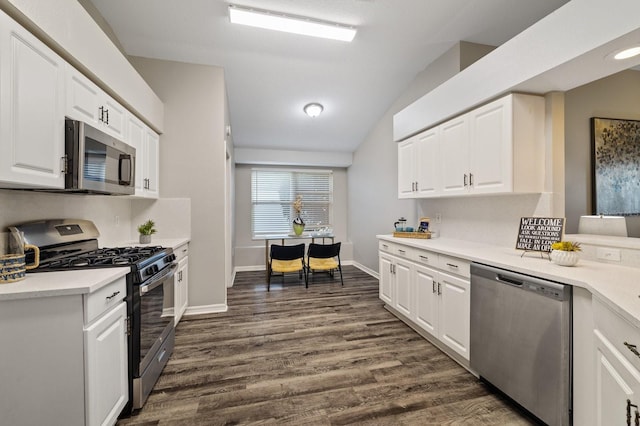 kitchen with stainless steel appliances, white cabinetry, vaulted ceiling, and dark wood-type flooring