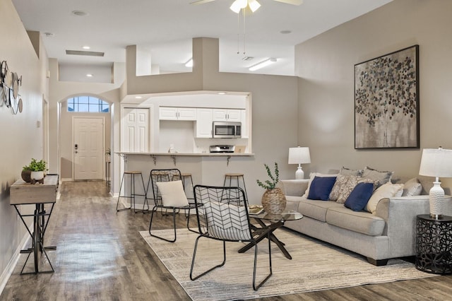 living room with a high ceiling, hardwood / wood-style flooring, and ceiling fan