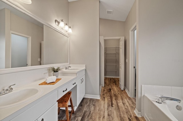 bathroom with a bath, vanity, and wood-type flooring