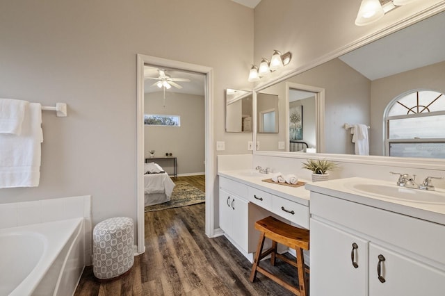 bathroom featuring ceiling fan, vanity, a tub to relax in, and hardwood / wood-style floors