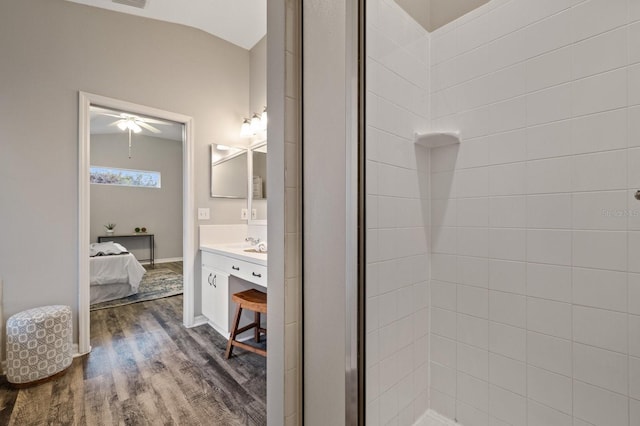 bathroom with vaulted ceiling, hardwood / wood-style floors, ceiling fan, walk in shower, and vanity