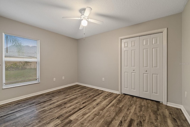 unfurnished bedroom with dark hardwood / wood-style flooring, a textured ceiling, ceiling fan, and a closet