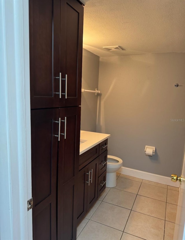 bathroom featuring toilet, vanity, tile patterned floors, and a textured ceiling