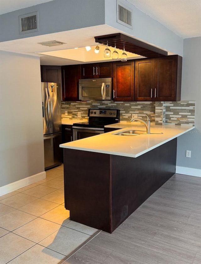 kitchen featuring kitchen peninsula, backsplash, sink, and stainless steel appliances