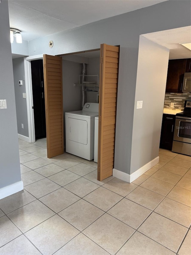 clothes washing area with washer / clothes dryer and light tile patterned floors