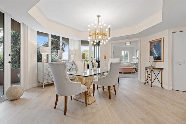 dining room with french doors, a tray ceiling, light hardwood / wood-style flooring, and a notable chandelier