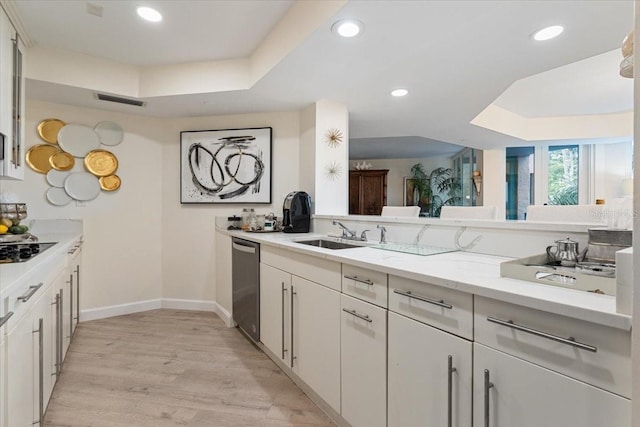 kitchen featuring dishwasher, sink, white cabinets, light stone counters, and a raised ceiling