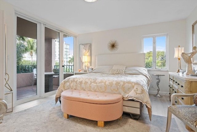 bedroom with expansive windows, access to outside, and light wood-type flooring