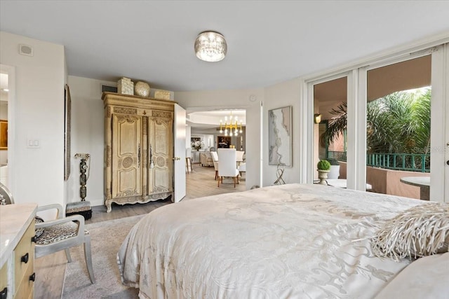 bedroom featuring access to exterior, light hardwood / wood-style floors, and a chandelier