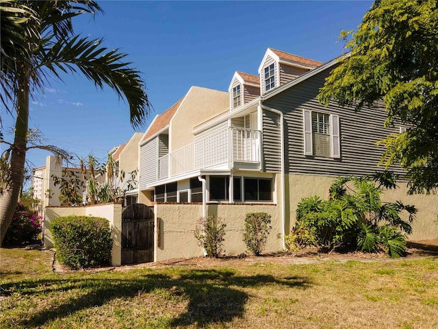 view of side of home featuring a lawn and a balcony