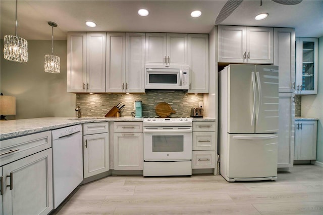 kitchen featuring tasteful backsplash, white appliances, decorative light fixtures, and light wood-type flooring