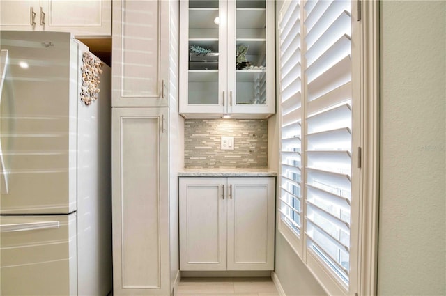 interior space featuring tasteful backsplash, light stone counters, white cabinets, and white refrigerator