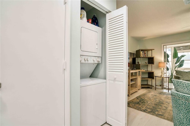 laundry room with light hardwood / wood-style flooring and stacked washing maching and dryer