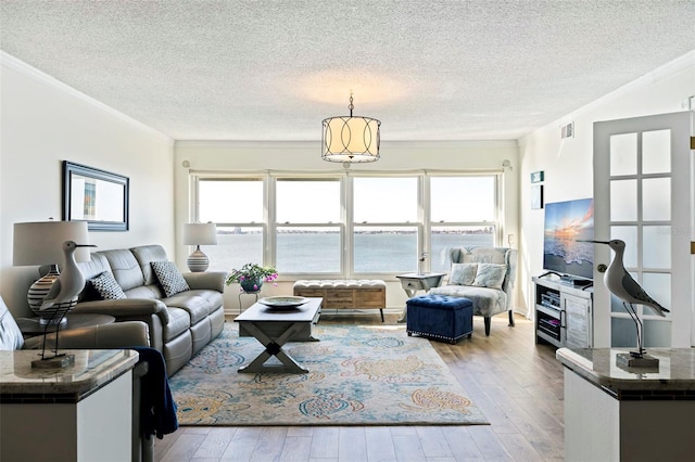 living room featuring a textured ceiling, ornamental molding, and light wood-type flooring