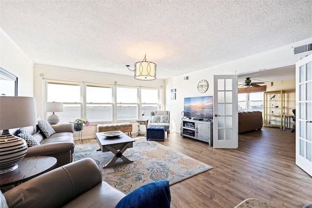 living room with french doors, a textured ceiling, and hardwood / wood-style floors