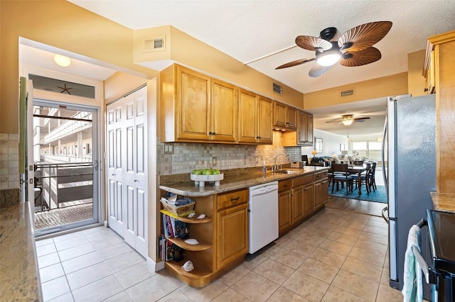 kitchen with dishwasher, dark stone countertops, sink, backsplash, and light tile patterned floors