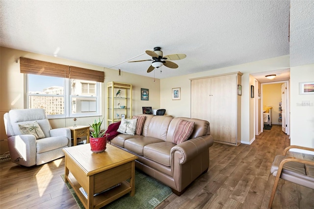 living room with a textured ceiling, ceiling fan, and dark hardwood / wood-style flooring