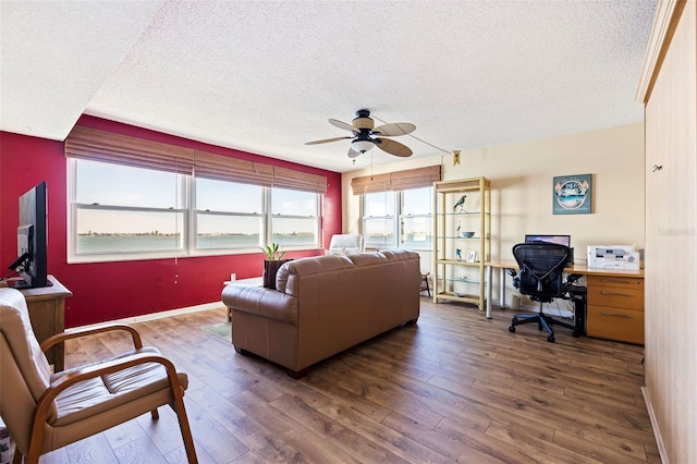 living room with a textured ceiling, ceiling fan, and dark hardwood / wood-style flooring