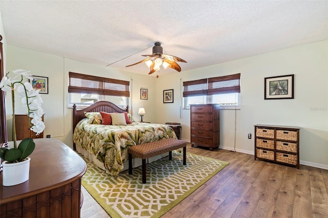 bedroom with a textured ceiling, ceiling fan, and wood-type flooring